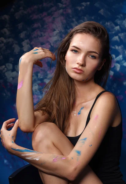 Young woman sitting near painting wall — Stock Photo, Image