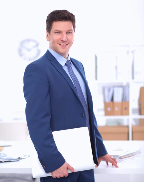 Zakenman of manager die op kantoor tegen zijn bureau staat — Stockfoto