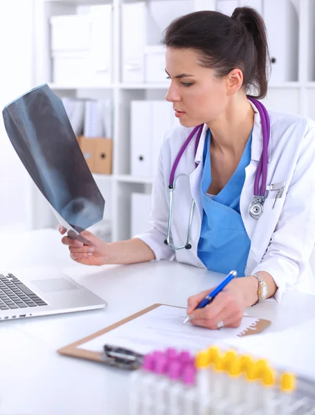 Jovem médica estudando radiografia sentada na mesa — Fotografia de Stock