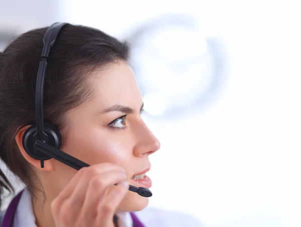 Médico con auriculares sentado detrás de un escritorio con portátil —  Fotos de Stock