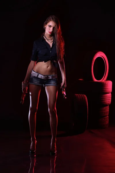 Porträt einer jungen Frau, die in der alten Garage steht. isoliert auf schwarzem Hintergrund — Stockfoto