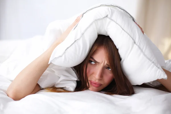 Mujer acostada en la cama y cerrando las orejas con almohada —  Fotos de Stock