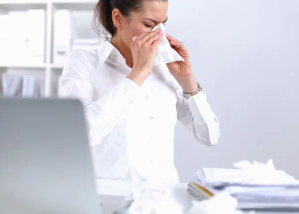 Junge Geschäftsfrau pustet sich die Nase, sitzt am Schreibtisch — Stockfoto