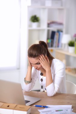 Masasında dizüstü bilgisayarla oturan bir iş kadınının portresi.