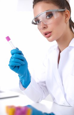 Kadın araştırmacı, beyaz arka planda izole edilmiş ilaç şişeleri ve mataralarla çevrili.