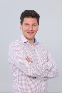 gri arka planı çapraz kollar ile ayakta, zeki genç bir adam portresi