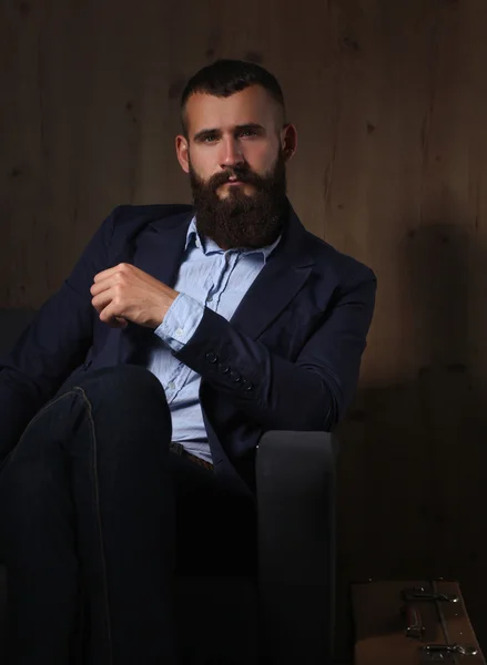 Businessman sitting the sofa in office lobby, isolated on dark background — Stock Photo, Image