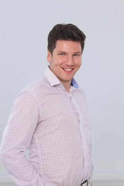 Portrait of a smart young man standing against gray background — Stock Photo, Image