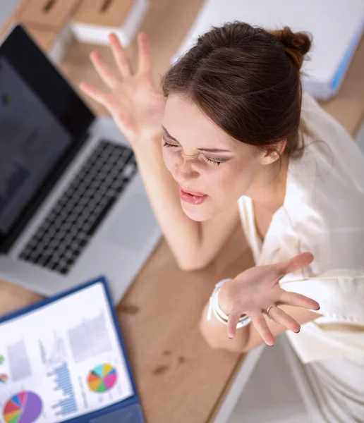 Porträtt av trött ung affärskvinna med bärbar dator på kontoret — Stockfoto