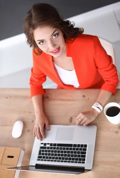 Mulher atraente sentada na mesa no escritório, trabalhando com computador portátil — Fotografia de Stock