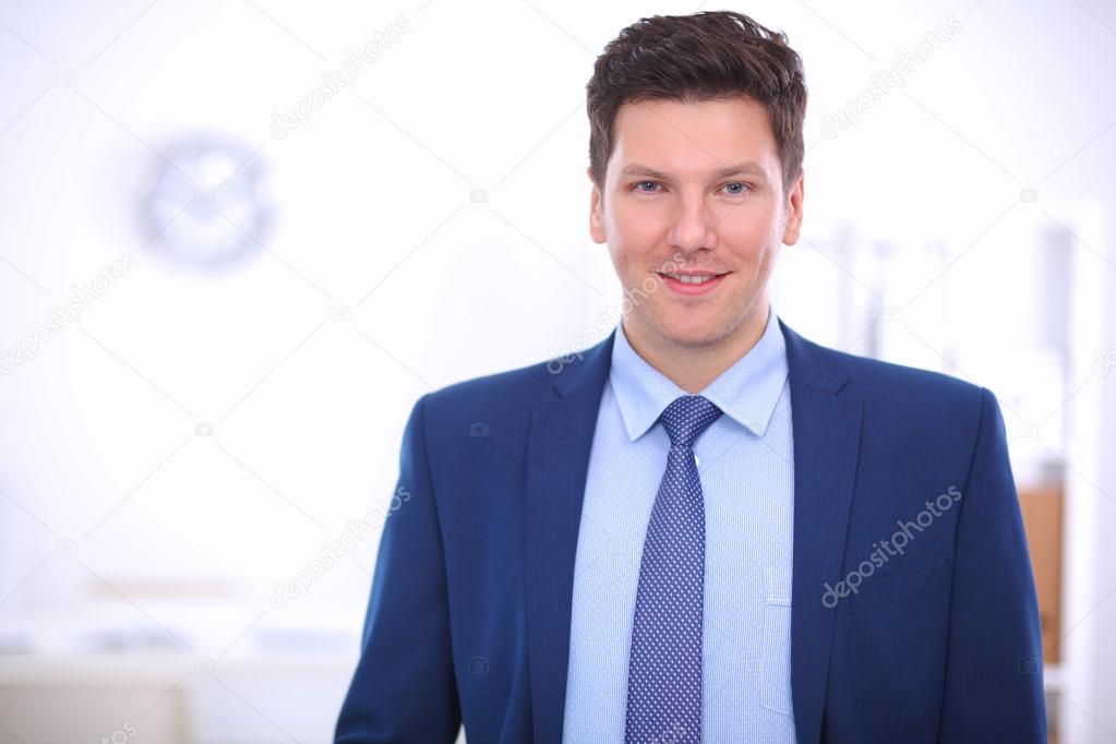 Business man or manager standing against his desk at the office