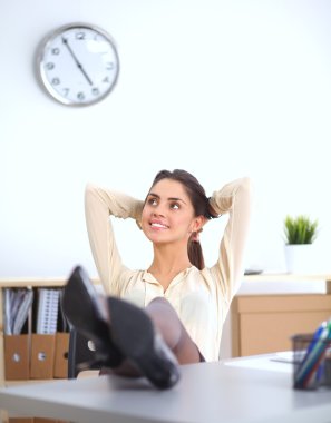 İş kadını ellerini başının arkasına koyup bir ofis sandalyesinde oturuyor.