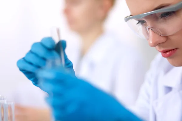 Woman researcher is surrounded by medical vials and flasks, isolated on white background — Stock Photo, Image