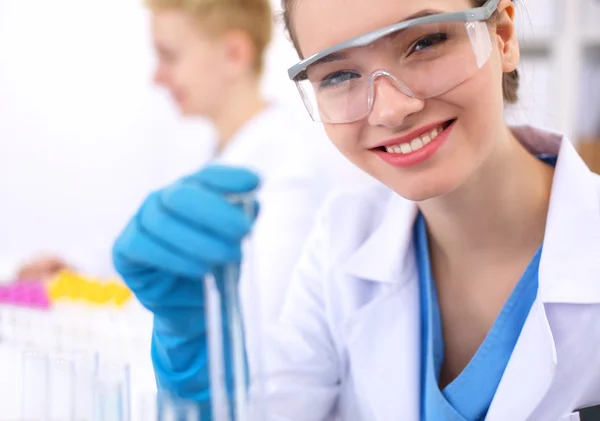 Woman researcher is surrounded by medical vials and flasks, isolated on white background — Stock Photo, Image