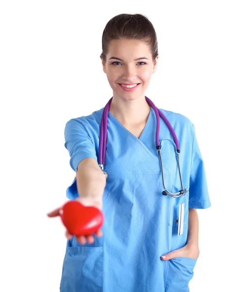 Mujer joven médico sosteniendo un corazón rojo, de pie sobre fondo gris — Foto de Stock