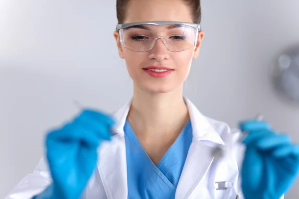 Attractive female dentist with tools , standing on gay background — Stock Photo, Image