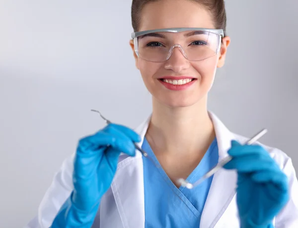 Aantrekkelijke vrouwelijke tandarts met gereedschap, staan op gay achtergrond — Stockfoto