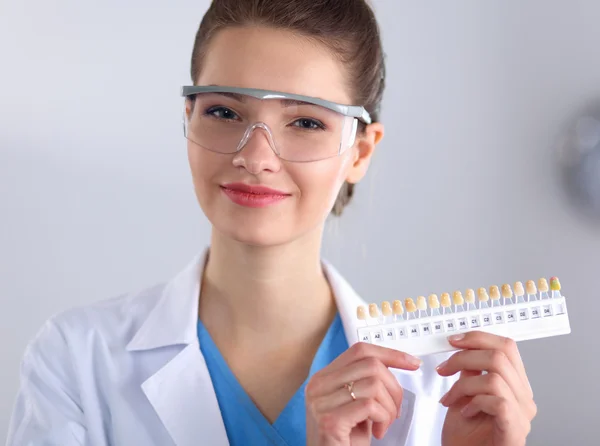 Attraktiv kvinnelig tannlege med verktøy, stående på homofil bakgrunn – stockfoto