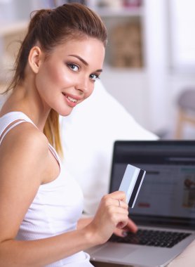 Kadın kredi kartı ve bilgisayarla online alışveriş yapıyor.