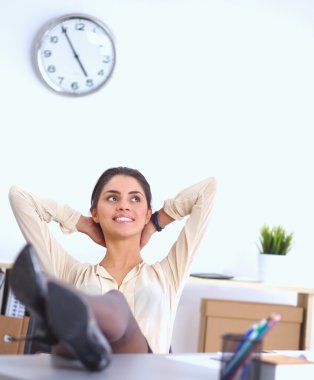İş kadını ellerini başının arkasına koyup bir ofis sandalyesinde oturuyor.