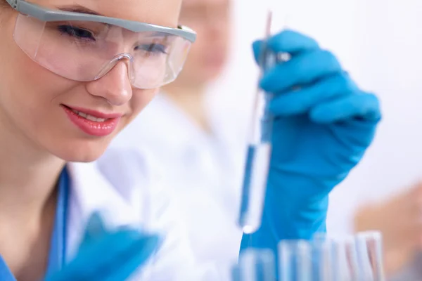 Woman researcher is surrounded by medical vials and flasks, isolated on white background — Stock Photo, Image