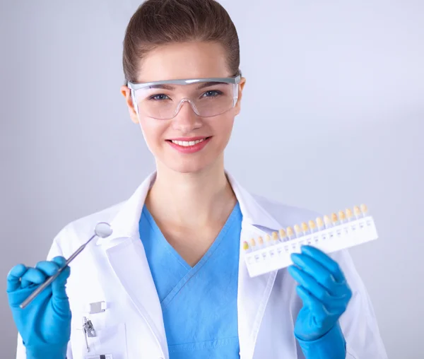 Attractive female dentist with tools , standing on gay background — Stock Photo, Image