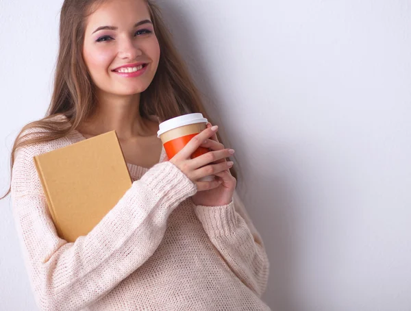Portrait d'une jeune femme avec une tasse de thé ou de café, tenant un livre — Photo