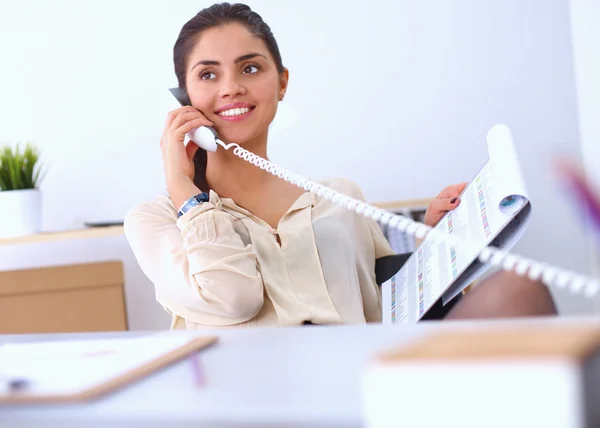 Jovem empresária sentada na mesa e conversando ao telefone — Fotografia de Stock