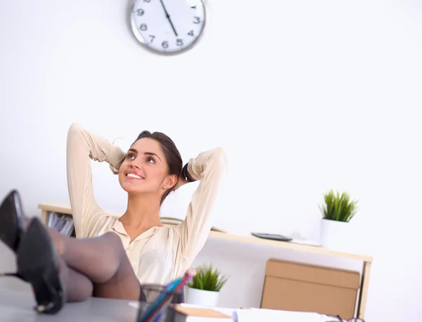 Geschäftsfrau entspannt sich mit den Händen hinter dem Kopf und sitzt auf einem Bürostuhl — Stockfoto