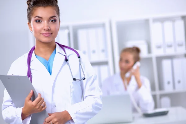 Médico sonriente con una carpeta en uniforme de pie en el hospital — Foto de Stock