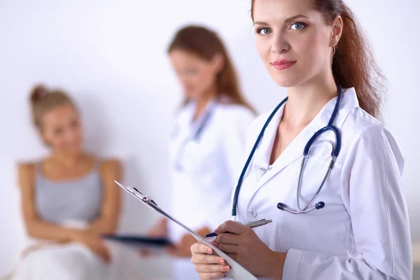 Sorridente medico donna con una cartella in uniforme in piedi in ospedale — Foto Stock