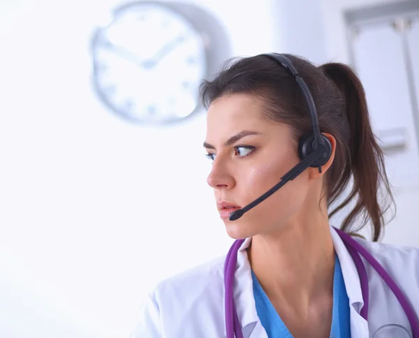 Dokter draagt een headset zittend achter een bureau met laptop — Stockfoto