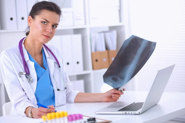 Jovem médica estudando radiografia sentada na mesa — Fotografia de Stock