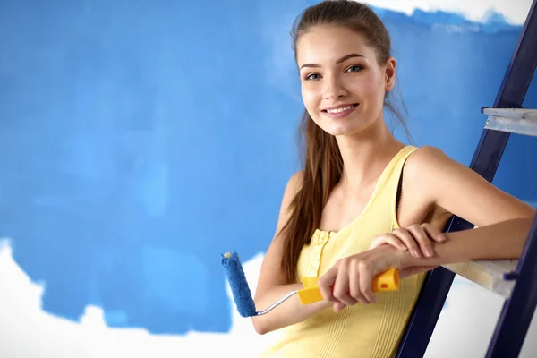 Feliz hermosa mujer joven haciendo pintura de pared, sentado en la escalera —  Fotos de Stock