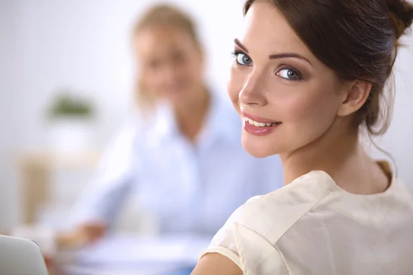 Due donne che lavorano insieme in ufficio, sedute sulla scrivania — Foto Stock