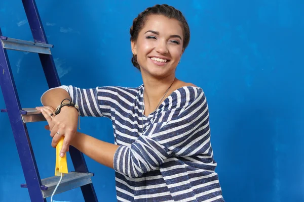 Feliz hermosa mujer joven haciendo pintura de pared, de pie en la escalera —  Fotos de Stock