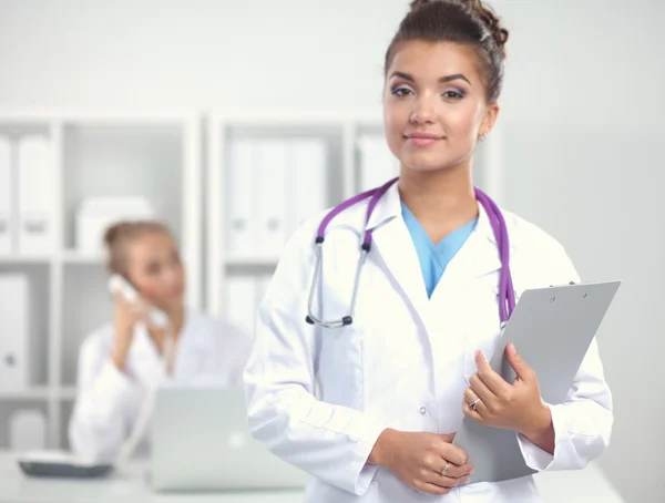 Médico sonriente con una carpeta en uniforme de pie en el hospital — Foto de Stock