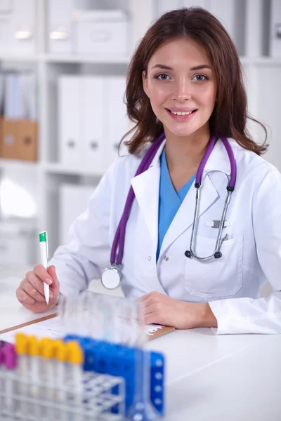 Woman researcher is surrounded by medical vials and flasks, isolated on white background — Stock Photo, Image