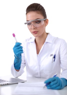 Kadın araştırmacı, beyaz arka planda izole edilmiş ilaç şişeleri ve mataralarla çevrili.