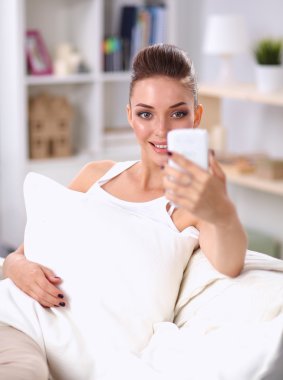 oturma odasında iletileri gönderme kanepede oturan güzel kadın