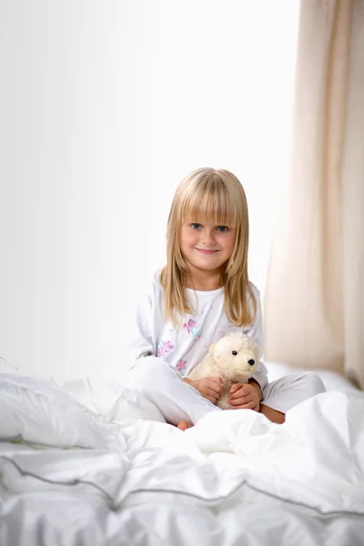 Kleines Mädchen mit Teddybär zu Hause auf dem Bett liegend — Stockfoto