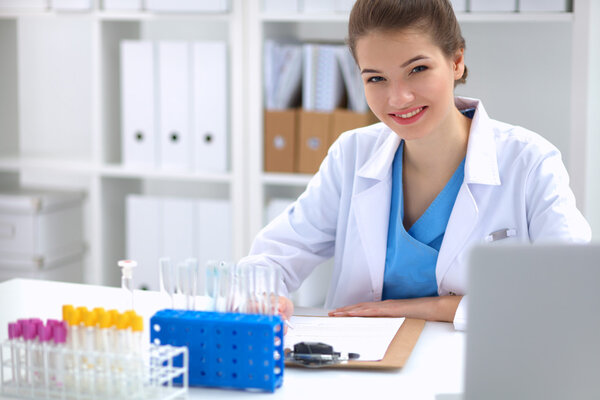 Woman researcher is surrounded by medical vials and flasks, isolated on white background