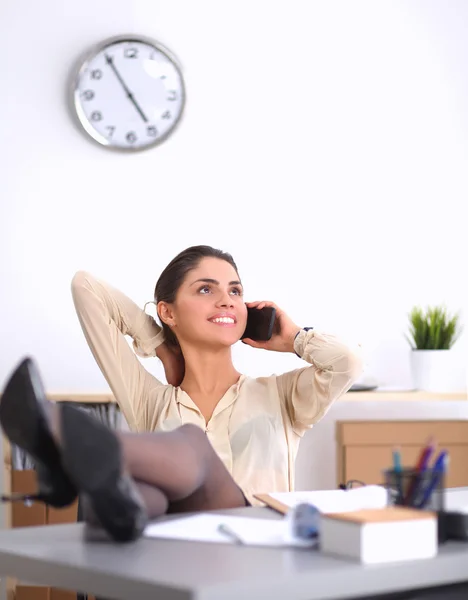 Giovane donna d'affari seduta alla scrivania e che parla al telefono — Foto Stock