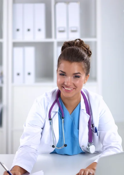 Doctora sentada en el escritorio y trabajando en un portátil en el hospital —  Fotos de Stock