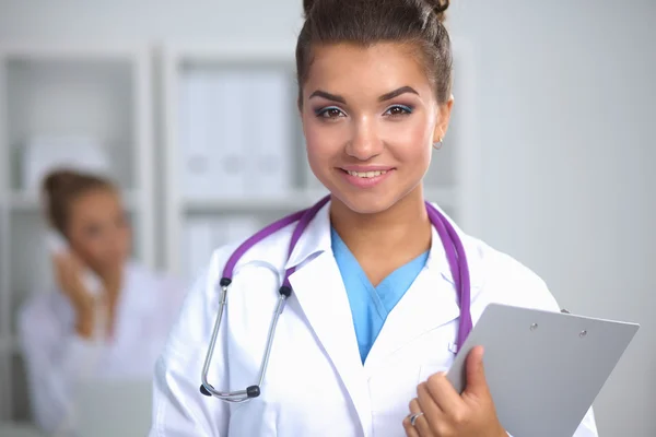 Médico sonriente con una carpeta en uniforme de pie en el hospital — Foto de Stock