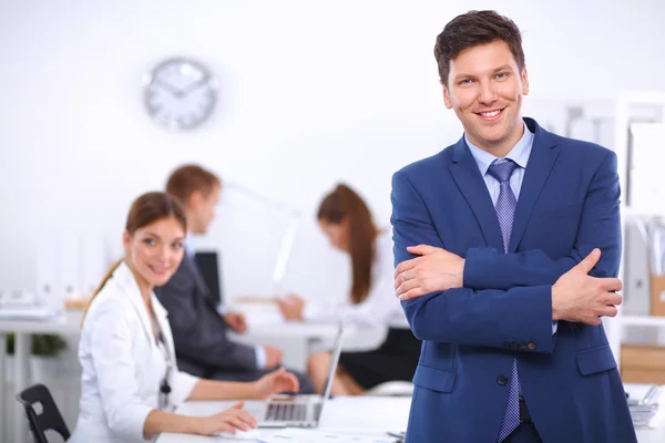 Successful business man standing with his staff in background at office — Stock Photo, Image