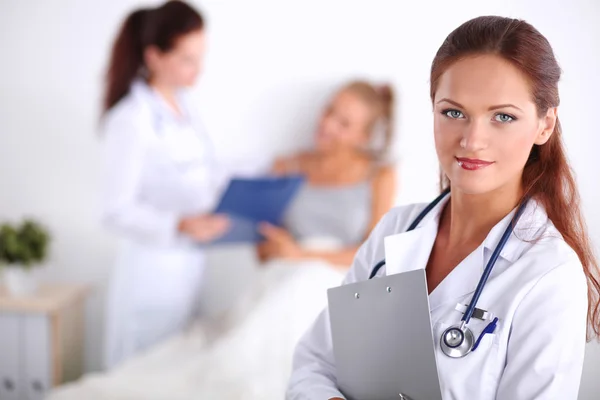 Médico sonriente con una carpeta en uniforme de pie en el hospital — Foto de Stock