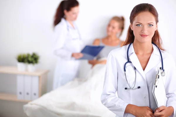 Médico sonriente con una carpeta en uniforme de pie en el hospital — Foto de Stock