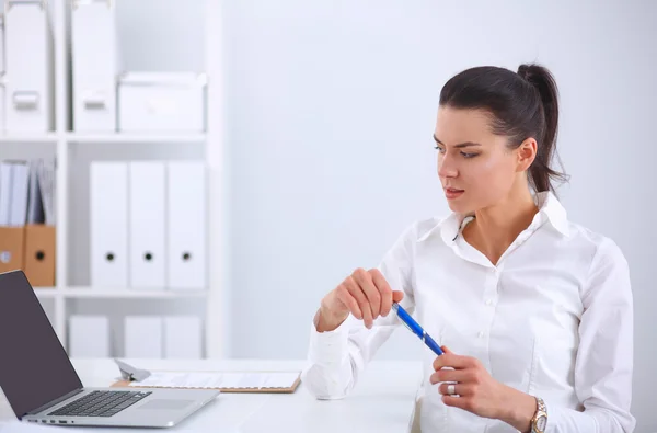 Aantrekkelijke zakenvrouw zit op een bureau met laptop in het kantoor — Stockfoto