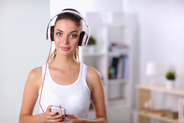 Mulher com fone de ouvido ouvindo música de pé em casa — Fotografia de Stock